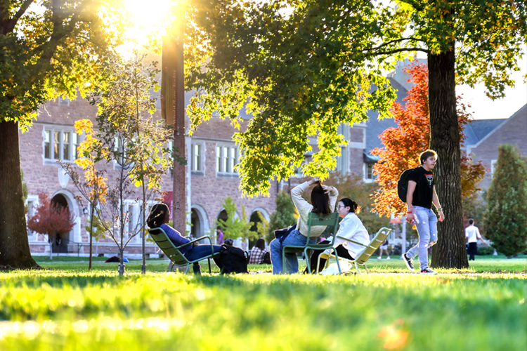 Students hanging out on campus while sitting in chairs